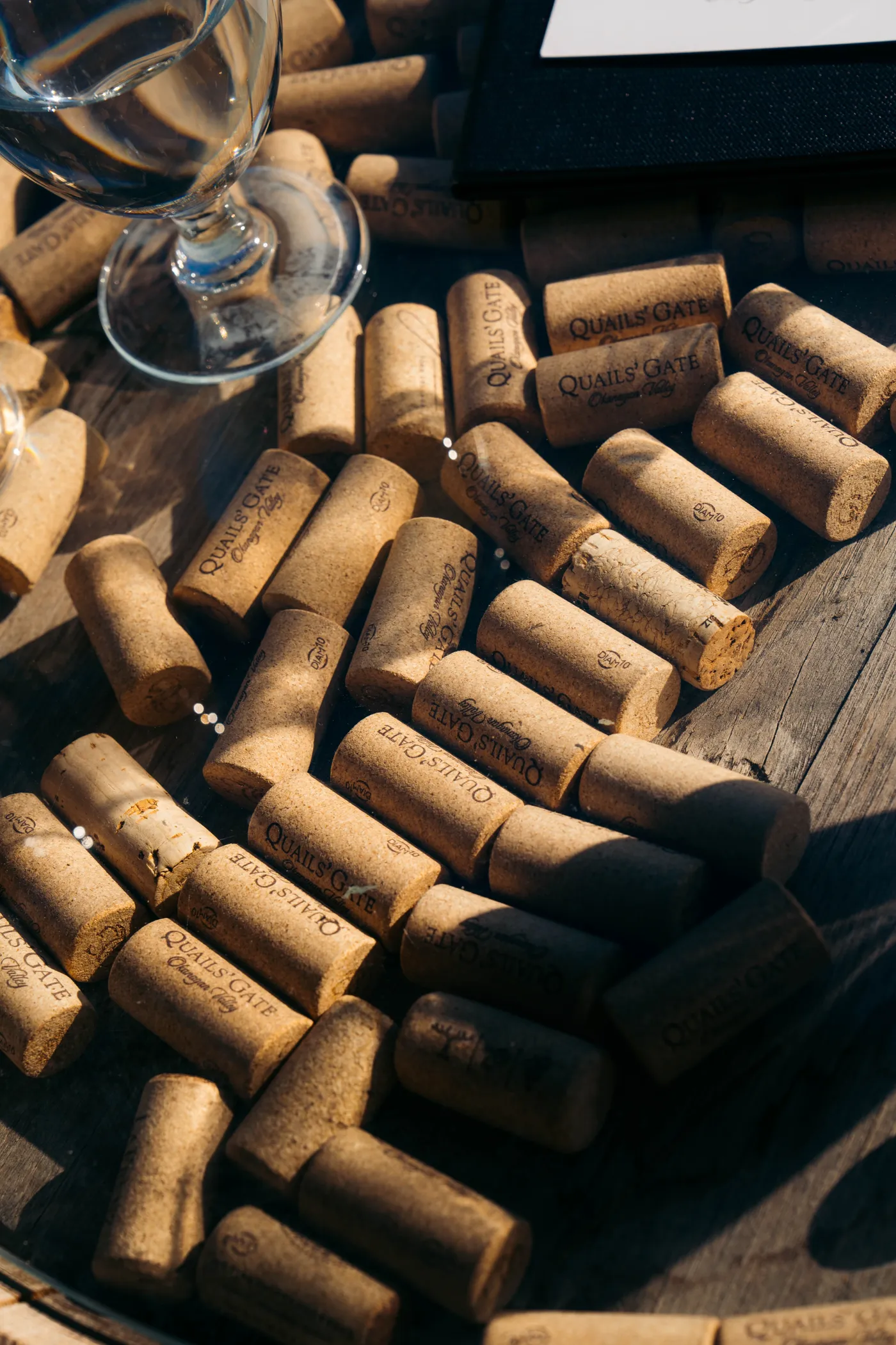 Wine corks and a glass of wine on a wooden surface at an Okanagan winery