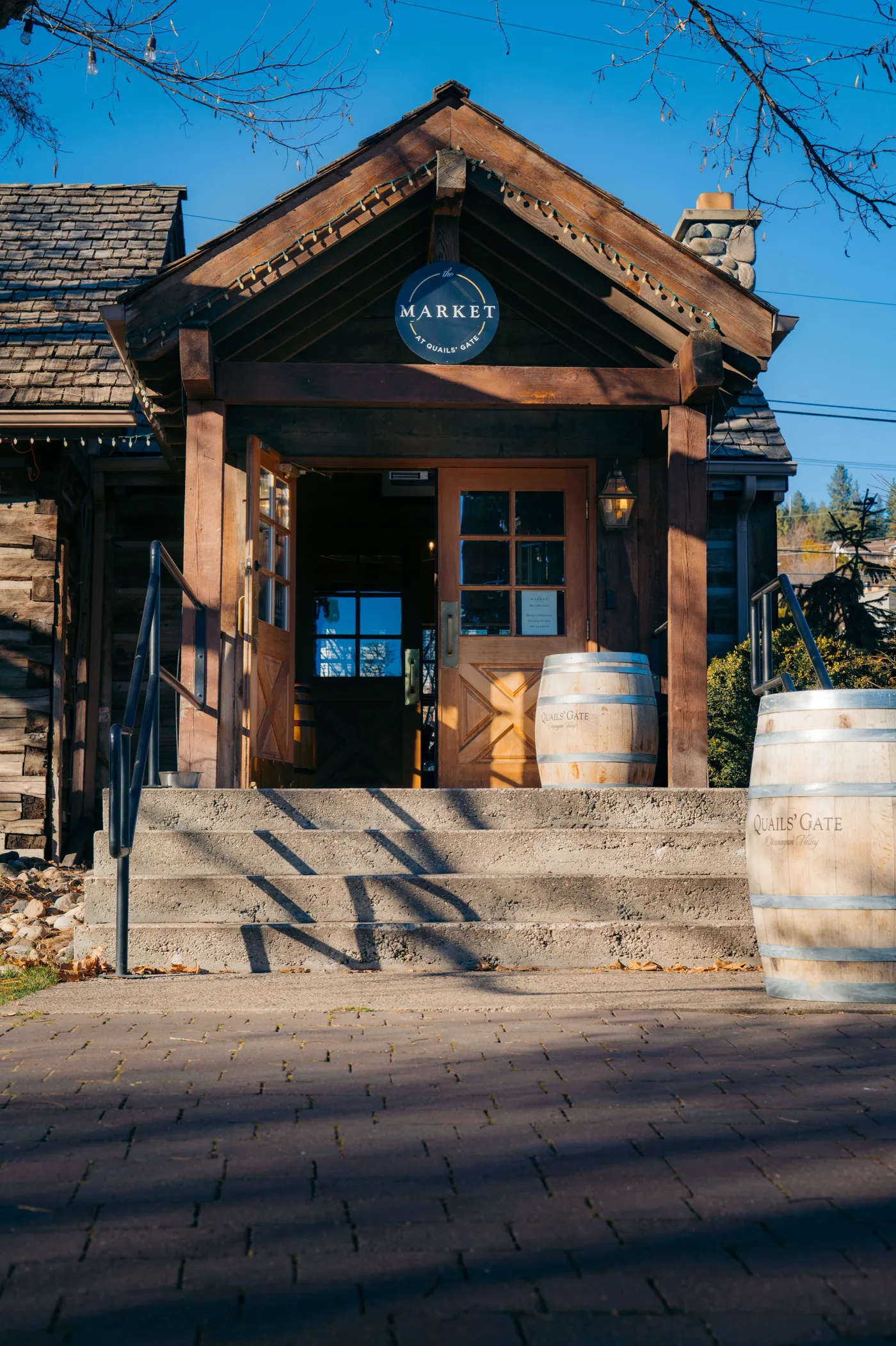 Rustic wooden winery market building with wine barrels displayed outside, Okanagan Valley BC