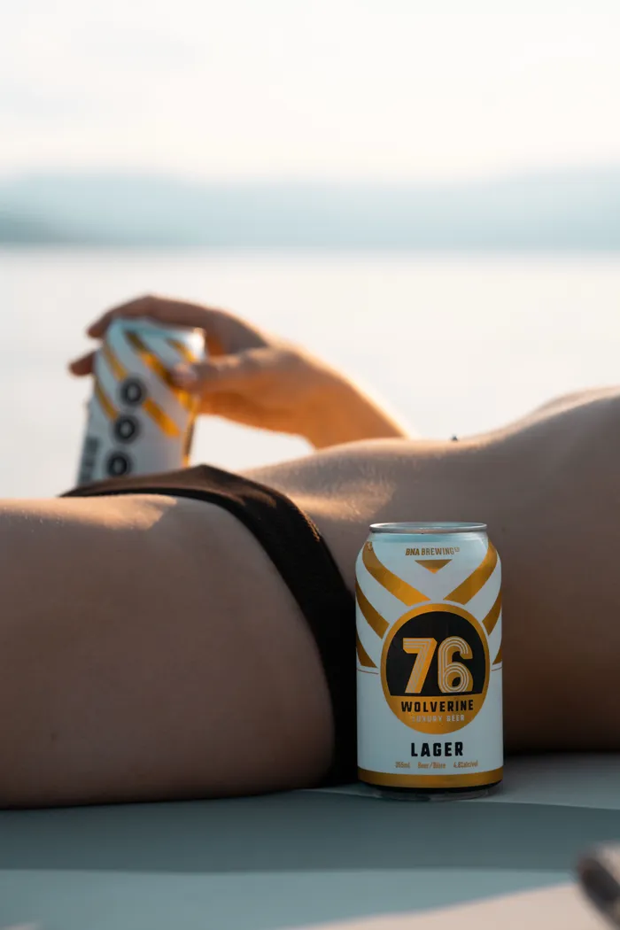 Beverage can on a beach towel at Okanagan Lake with a kite in the background at golden hour